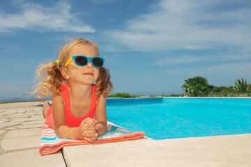 Young girl enjoys pool day with sunglasses, lay down on edge - 755578509