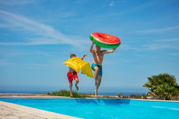 Dad and son with floaties jump to pool ready for summer fun - 755579361
