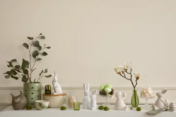 Fototapeten Interior design of easter living room interior stylish sideboard, colorful easter eggs, easter bunny sculpture, vase with leaves, magnolia and personal accessories Home decor. Template. © FollowTheFlow