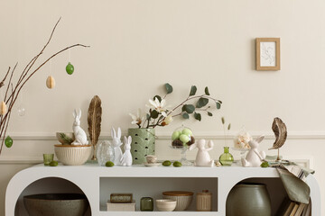 Interior design of easter living room interior stylish sideboard, colorful easter eggs, easter bunny sculpture, vase with leaves, magnolia and personal accessories Home decor. Template.