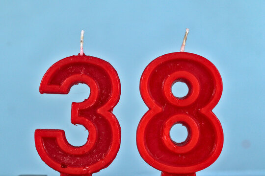 close up on red number thirthy eighth birthday candle on a white background.
