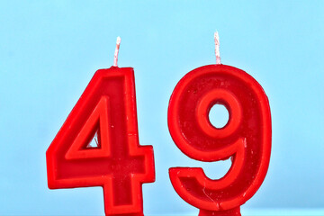 close up on a red number forty ninth birthday candle on a white background.
