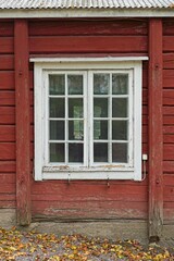 White framed window on a old red painted wooden building.
