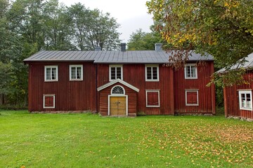 Obraz premium Old traditional style red wooden building in cloudy autumn weather, Finland.