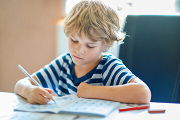 Little boy playing with toddler sister outdoors. Sibling drawing with chalks and play with soft...