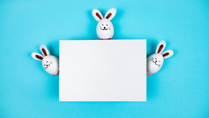 Three Easter bunnies made of white chicken eggs behind a sheet of white paper. Happy Easter Bunny...