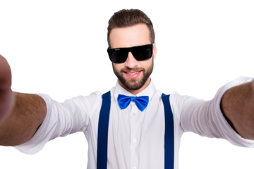 Self portrait of cool famous singer wearing bow, shirt, suspenders shooting selfie on front camera with two hands isolated on grey background