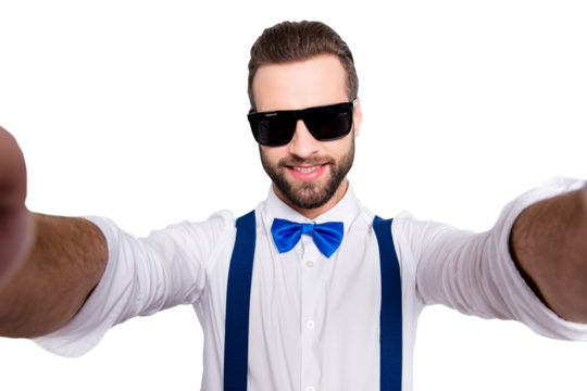 Self portrait of cool famous singer wearing bow, shirt, suspenders shooting selfie on front camera with two hands isolated on grey background
