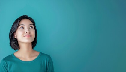 Fototapeta premium Young asian woman isolated on background having doubts while looking up