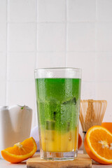 Orange Matcha Lemonade, Cold asia fruit cocktail with green matcha and orange citrus drink on white background, copy space