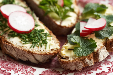 Spring wild edible plants - onion grass, garlic mustard and ground elder, on slices of sourdough bread, closeup