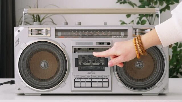 Woman hand puts cassette into deck recorder playing music close up. Analog tape recorder plays  audio cassette spins plays music close up slide top front. Retro tape reels rotate 