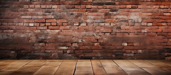 An old red brick wall stands behind a wooden floor creating an abstract and empty interior background texture. The contrast between the rustic bricks and the smooth wooden planks provides a simple yet