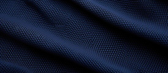 Detailed close-up of a dark blue fabric, specifically a sport clothing jersey with an air mesh texture. The fabric has abstract wavy patterns creating an elegant texture background.