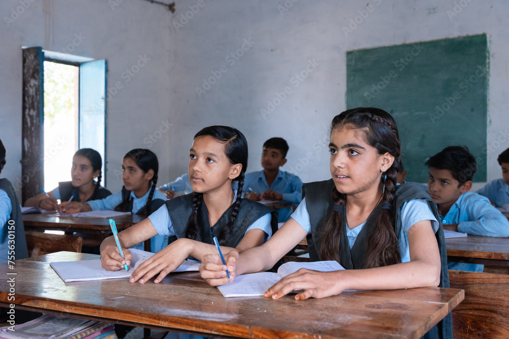 Wall mural Group of indian village students in school uniform sitting in classroom doing homework, studying. Education concept