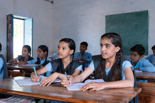 Group of indian village students in school uniform sitting in classroom doing homework, studying. Education concept