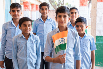 Group of happy village boys in school uniform celebrating independence day with Indian flag in hand - concept of independence, republic day, patriotism and freedom.