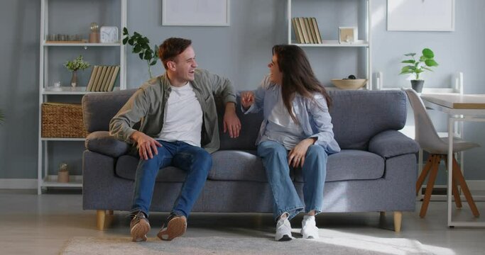Happy couple jumping on sofa laughing and giving high-fives. Happy couple smiling joy fills room happy couple revels in togetherness cherishing every moment of their playful antics Jumping on sofa