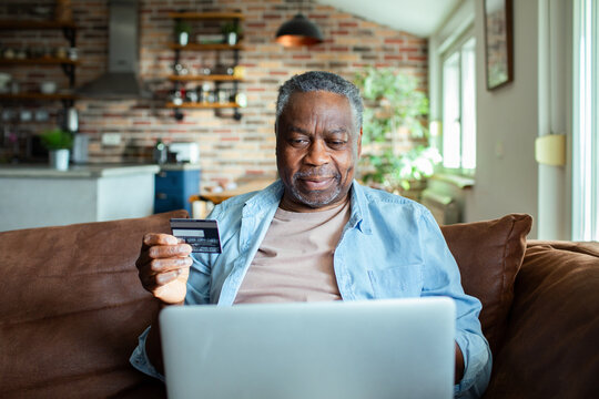 Mature man online shopping with credit card and laptop at home