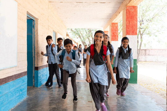 Happy group of indian rural children in school uniform standing looking at camera in school corridor. Education concept