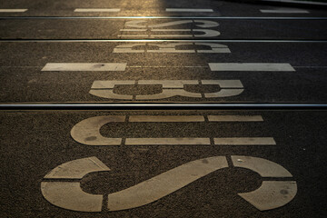 The photo captures a road scene featuring a BUS road sign and a dedicated bus lane. Bathed in warm,...