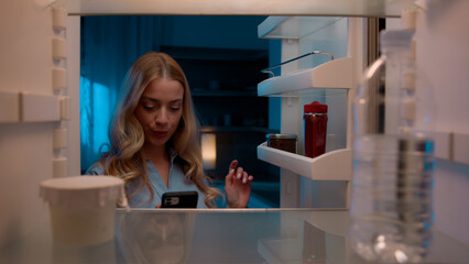Point of view POV inside refrigerator Caucasian girl hungry woman open fridge at home kitchen look at empty shelves order food products delivery with mobile phone app online service web store shopping - obrazy, fototapety, plakaty