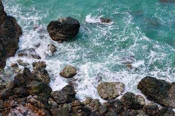 high-angle landscape of rocks by the sea The view from the mountain in the island with the cool breeze, green trees and the blue sea. The air is nice and refreshing in the summer in Thailand.