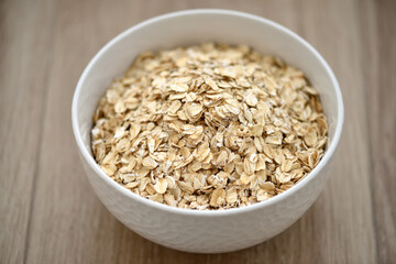Dry rolled oat flakes oatmeal in plate on wooden table - 755642774