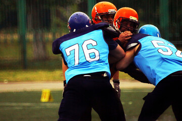 Two Football Players in American Football in blue and black uniforms fight with opponents	

