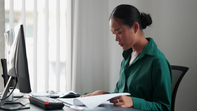 Asian businesswoman working diligently, reading documents and staying informed about her job at the office