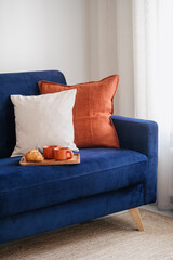 Comfort couch, decorative cushions and wooden tray with cups and croissant