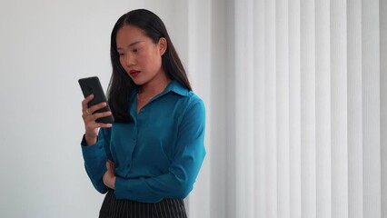 Asian businesswoman using a smartphone to stay informed with the latest news at her office. Keeping up-to-date for informed decision-making
