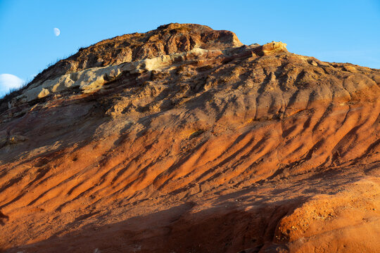 Multicolored sandstone rocks in the Almagreira beach in the Peniche area of the Center region of Portugal at sunset.