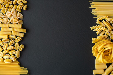 Italian Pasta variations on Black graphite board background, top view. Italian dry Pasta variation...