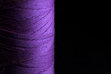 Spool of purple thread for sewing with black horizontal background