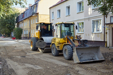 Bulldozer and roller for laying asphalt on a city street with removed pavement. Repair and...