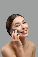 Skin care. Young woman removing oil from face using blotting papers. Beautiful girl model with smooth and healthy skin. Beauty spa concept. Cosmetology, cosmetics. Facial treatment