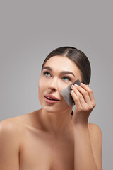Skin care. Young woman removing oil from face using blotting papers. Beautiful girl model with smooth and healthy skin. Beauty spa concept. Cosmetology, cosmetics. Facial treatment