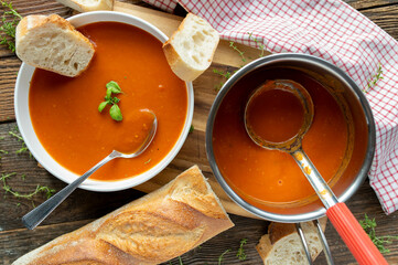 Homemade tomato soup with baguette on a deep plate with spoon