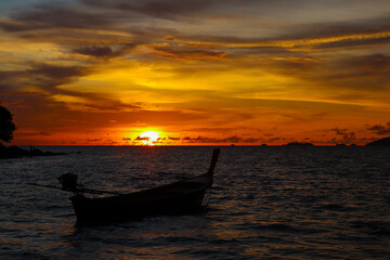 Fototapeta na wymiar Sunset Serenity: Traditional Thai Wooden Boat on the Horizon