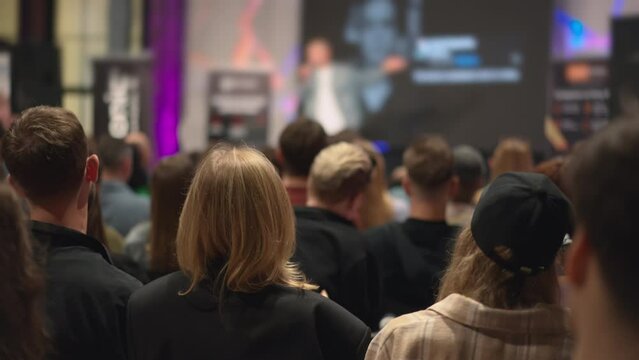 Audience of young professionals observes tech innovation presentation, engaging with new industry trends. Innovators share cutting-edge technologies at a conference, presenting to youthful audience.