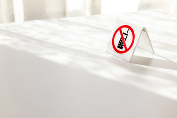 白いテーブルに置かれた携帯電話使用禁止の札
