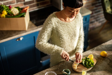 Asian woman cutting fruit for healthy smoothie in the kitchen