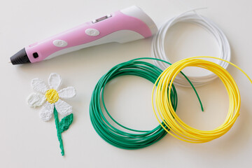 3d pen, kit of colourful plastic filament and flower on white background