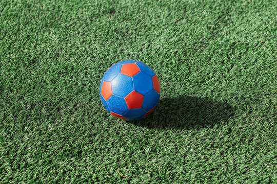 Fototapeta Colorful soccer ball on lush green artificial turf