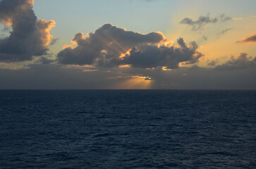 Sunset at sea, reflections on water surface, cloudy sky with sunset light sunrays