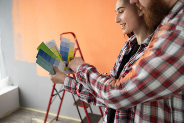 Happy young couple choosing paint colors from palette for new house. Home, moving, decoration,...