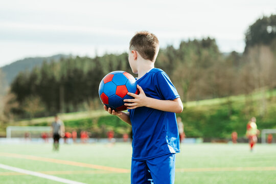 Young soccer player holding a ball on the field