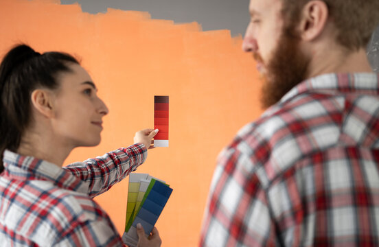 Home, moving, renovation and wall painting concept. Young couple choosing color with palette in their new house
