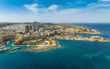 Aerial drone view of St. Julian's city and modern high buildings. Day. Maltese island, Mediterranean sea